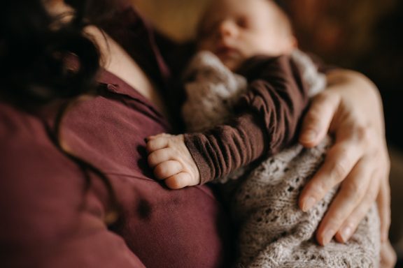 Nahaufnahme eines Neugeborenen auf dem Arm seiner Mutter