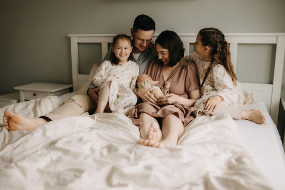 Familie mit Kindern und Neugeborenem gemeinsam auf dem Bett in der Nähe von Weimar