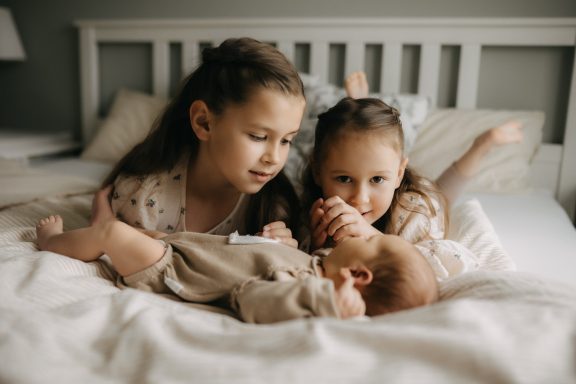 Geschwister kuscheln mit Baby